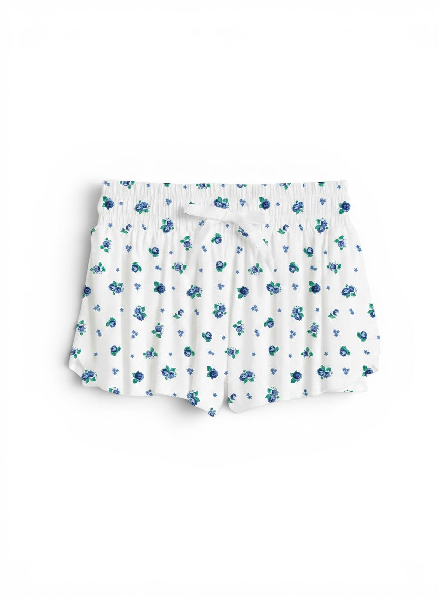 Vann & Liv Suzette floral fly away shorts in blue floral print. White shorts with elastic waistband and drawstring, featuring built-in compression shorts and a pleated design.