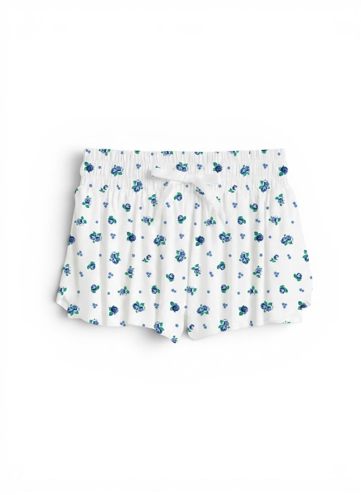 Vann &amp; Liv Suzette floral fly away shorts in blue floral print. White shorts with elastic waistband and drawstring, featuring built-in compression shorts and a pleated design.