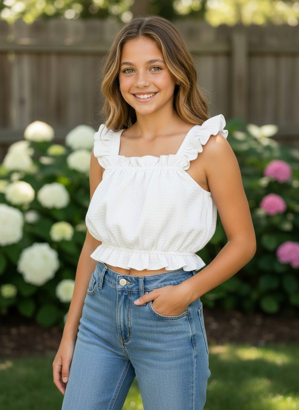Vann & Liv light blue gingham crop tank top with flutter sleeves and ruffled hem, worn by a smiling girl in denim shorts.