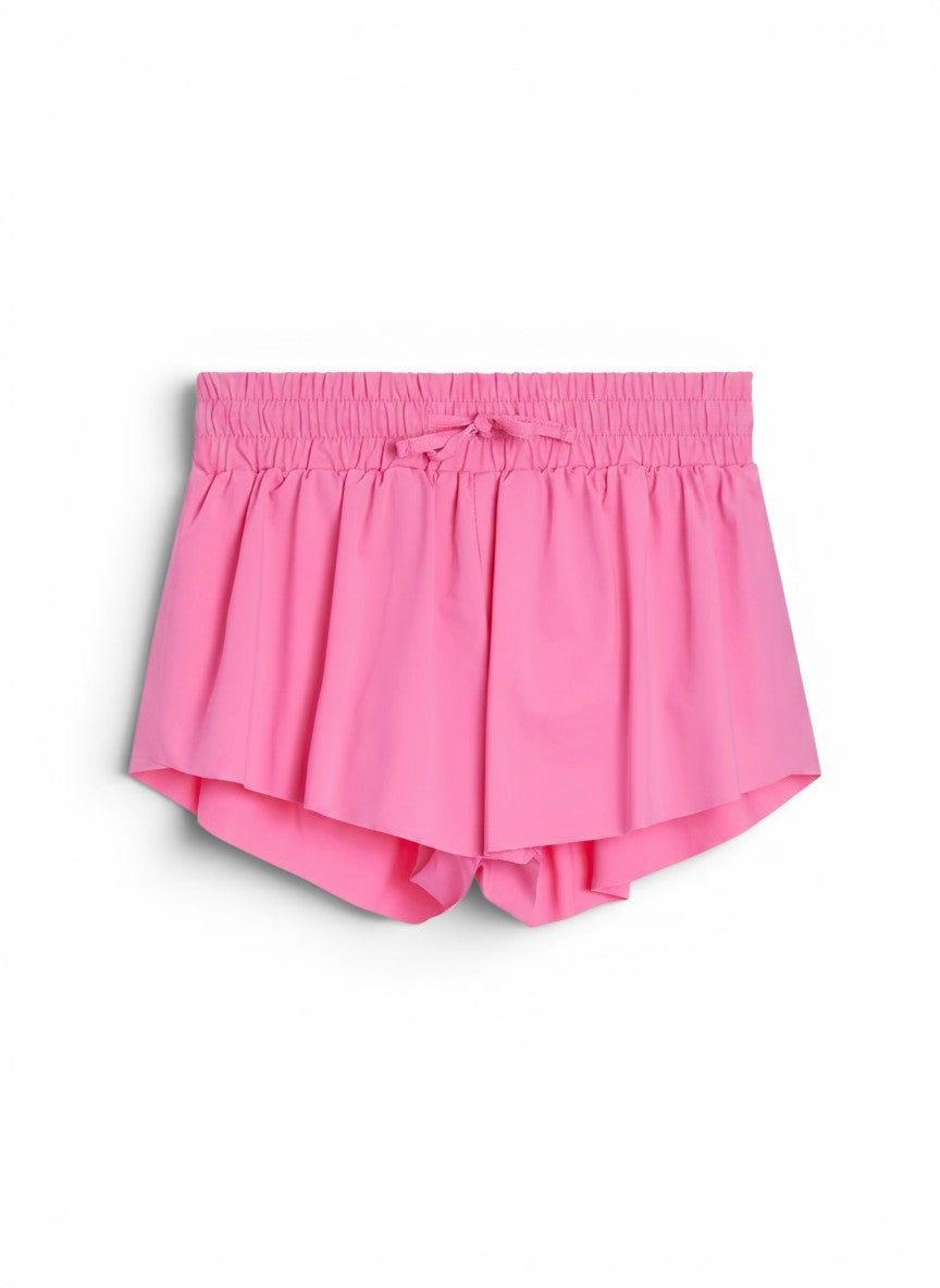 Vann & Liv Suzette Fly Away shorts in bubble gum pink. Pleated design with elastic waistband and drawstring. Built-in compression shorts.